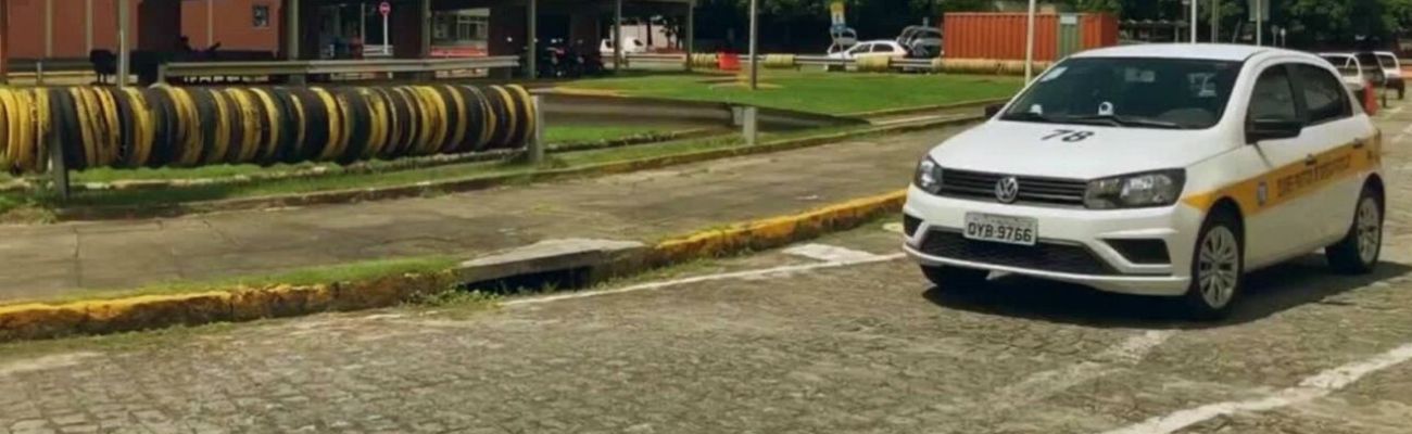 Carro branco passando numa via do trecho da pista para a prova prática de habilitação
