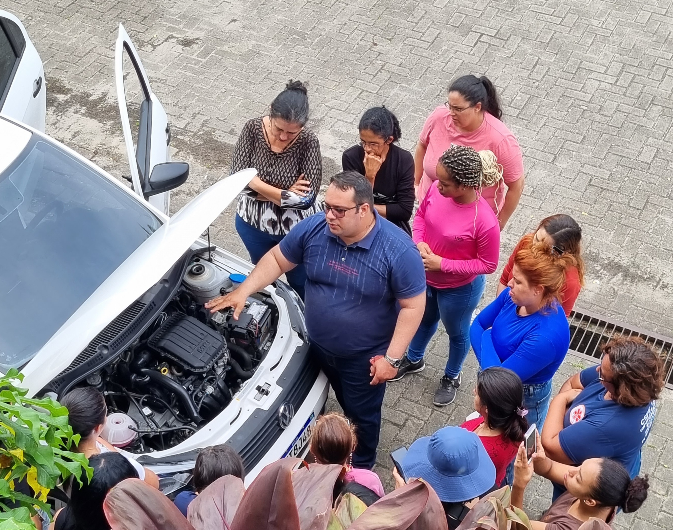 Foto colorida de instrutor explicando mecânica a mulheres