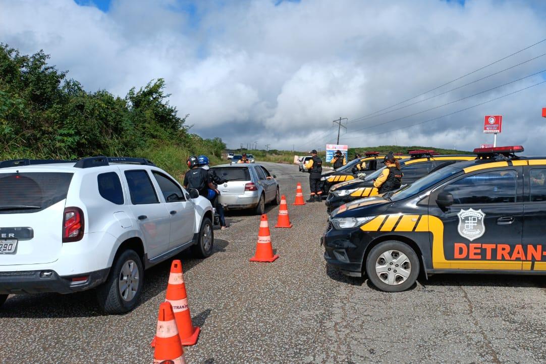 Foto colorida com agentes de trânsito e veículos do Detran em estrada