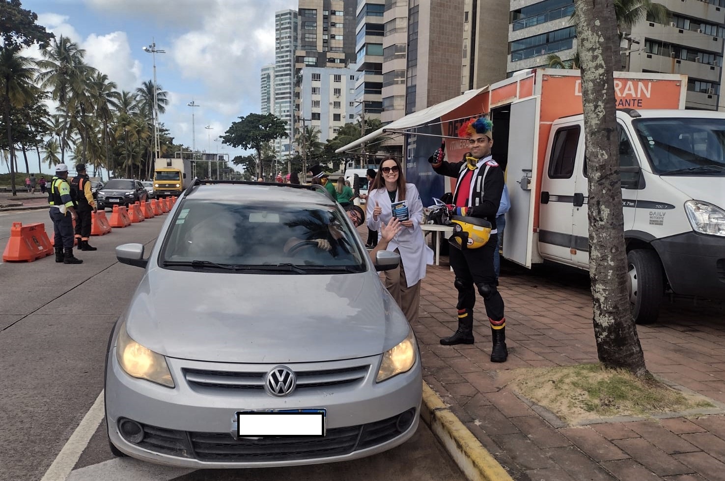 Fotografia colorida mostrando ação do Dia do Motorista com turma do Fom-Fom na Av. Boa Viagem, Recife