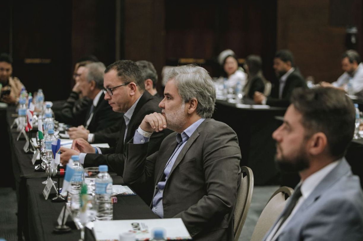 Na foto, o Diretor Presidente do DETRAN-PE, Gustavo Carneiro Leão, de perfil, com a mão direita no queixo e com teu cotovelo encostado na mesa. Na foto, ele está ao centro da imagem, sentado na cadeira, ao seu redor, outros Diretores Presidente dos DETRAN’s do Brasil. Essa imagem é do 74º Encontro Nacional dos Detrans, que aconteceu em Florianópolis (SC).