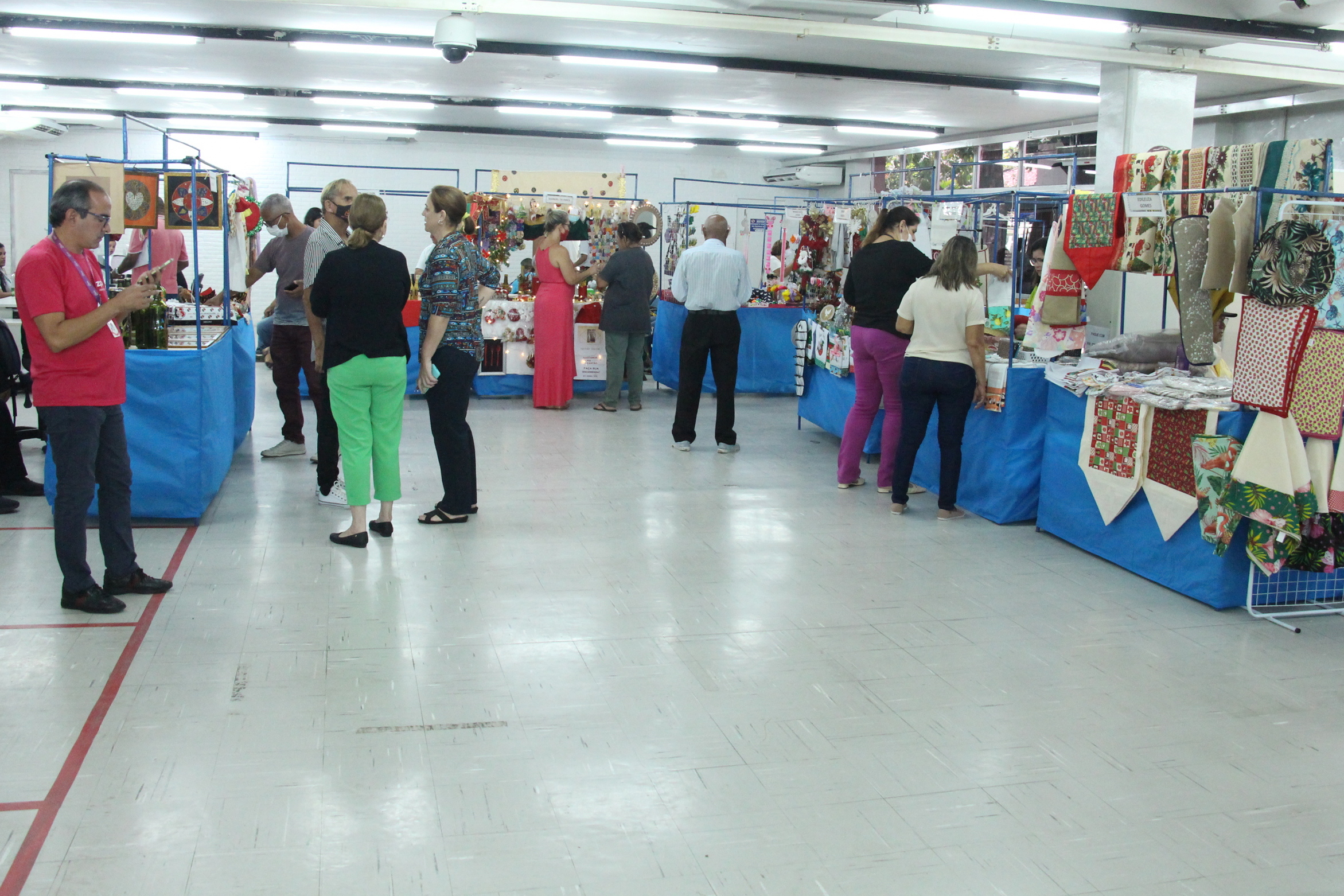 Fotografia colorida do salão de entrada do Detran-PE mostrando pessoas visitando as barraquinhas da feira