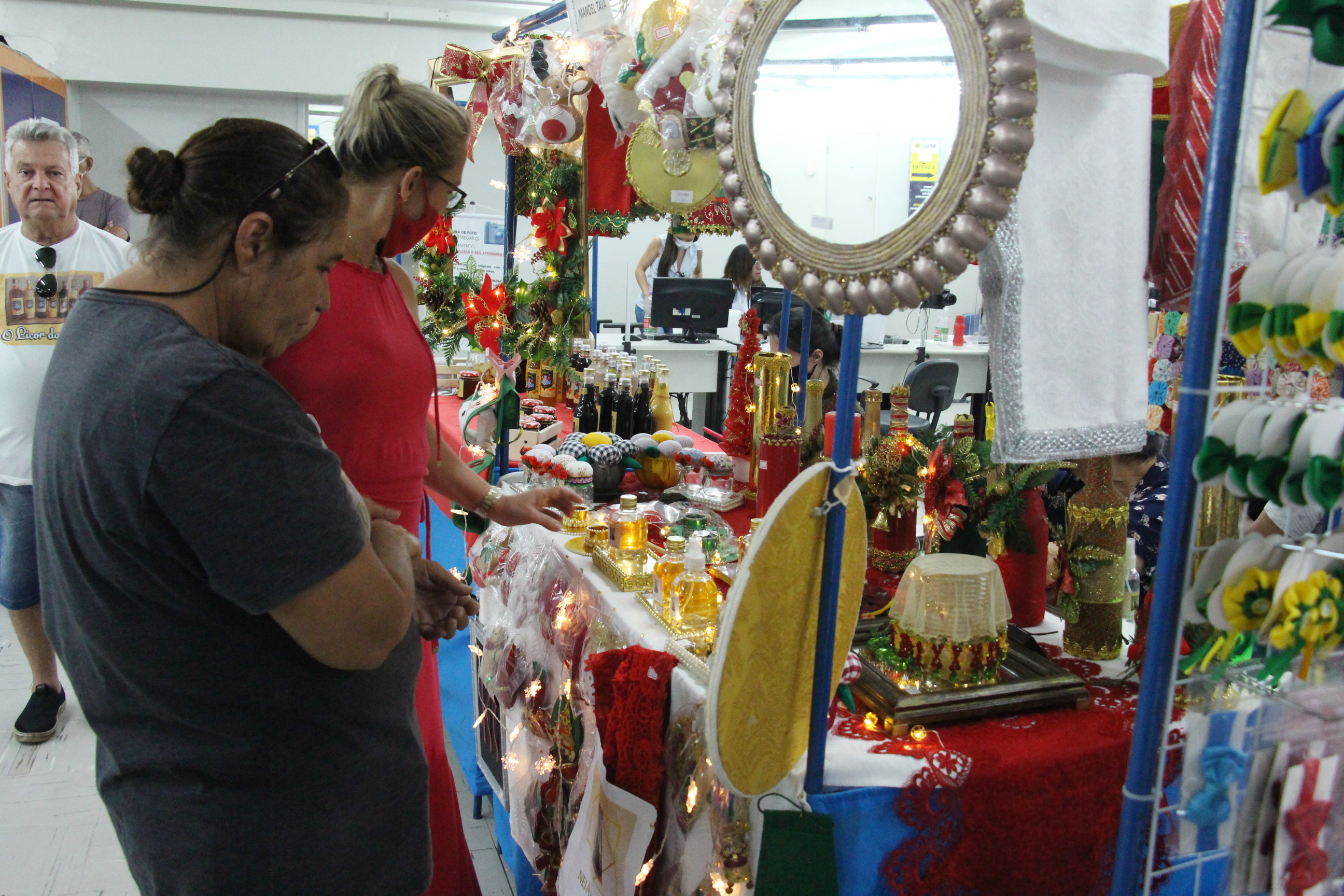 Foto colorida em “zoom” mostra artigos para decoração natalina como laços, peças douradas e pequenas árvores de natal