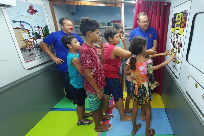 Na foto, educador de educação de trânsito do DETRAN-PE mostrando atividade lúdica sobre os cuidados no trânsito às crianças. 