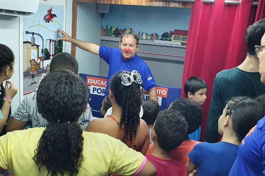 Na foto, educador de educação de trânsito do DETRAN-PE mostrando atividade lúdica sobre os cuidados no trânsito às crianças. 