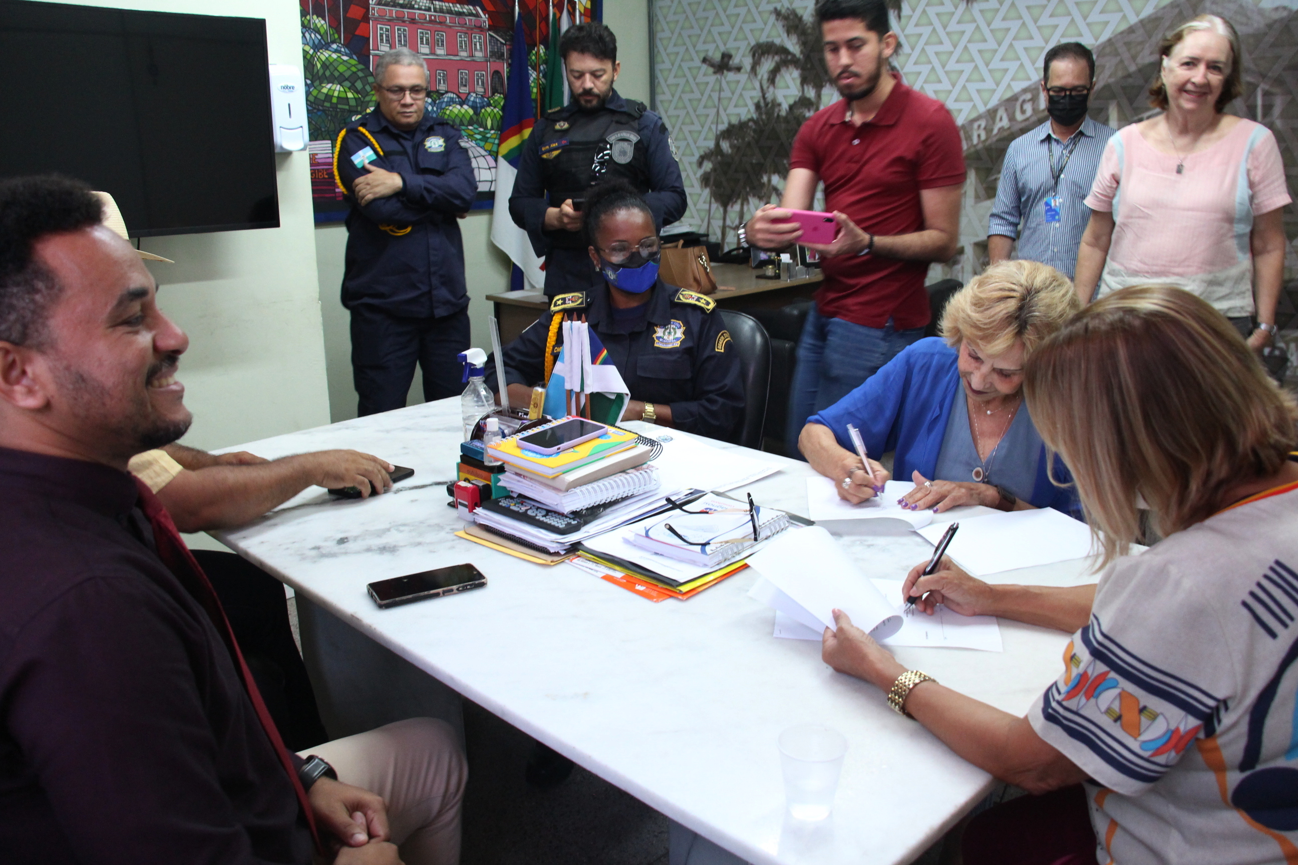 Na foto, a Coordenadora de Educação de Trânsito, Imprensa e Publicidade Institucional do DETRAN-PE, Jô Lima, e a Prefeita de Camaragibe, Nadegi Queiroz, assinaram convênio de cooperação técnica para XX Feira de Educação de Trânsito. Estão presentes na foto, o Gerente da Escola Pública de Trânsito do DETRAN-PE, Ivson Correia; representantes da guarda civil municipal e da Prefeitura; além da imprensa. 