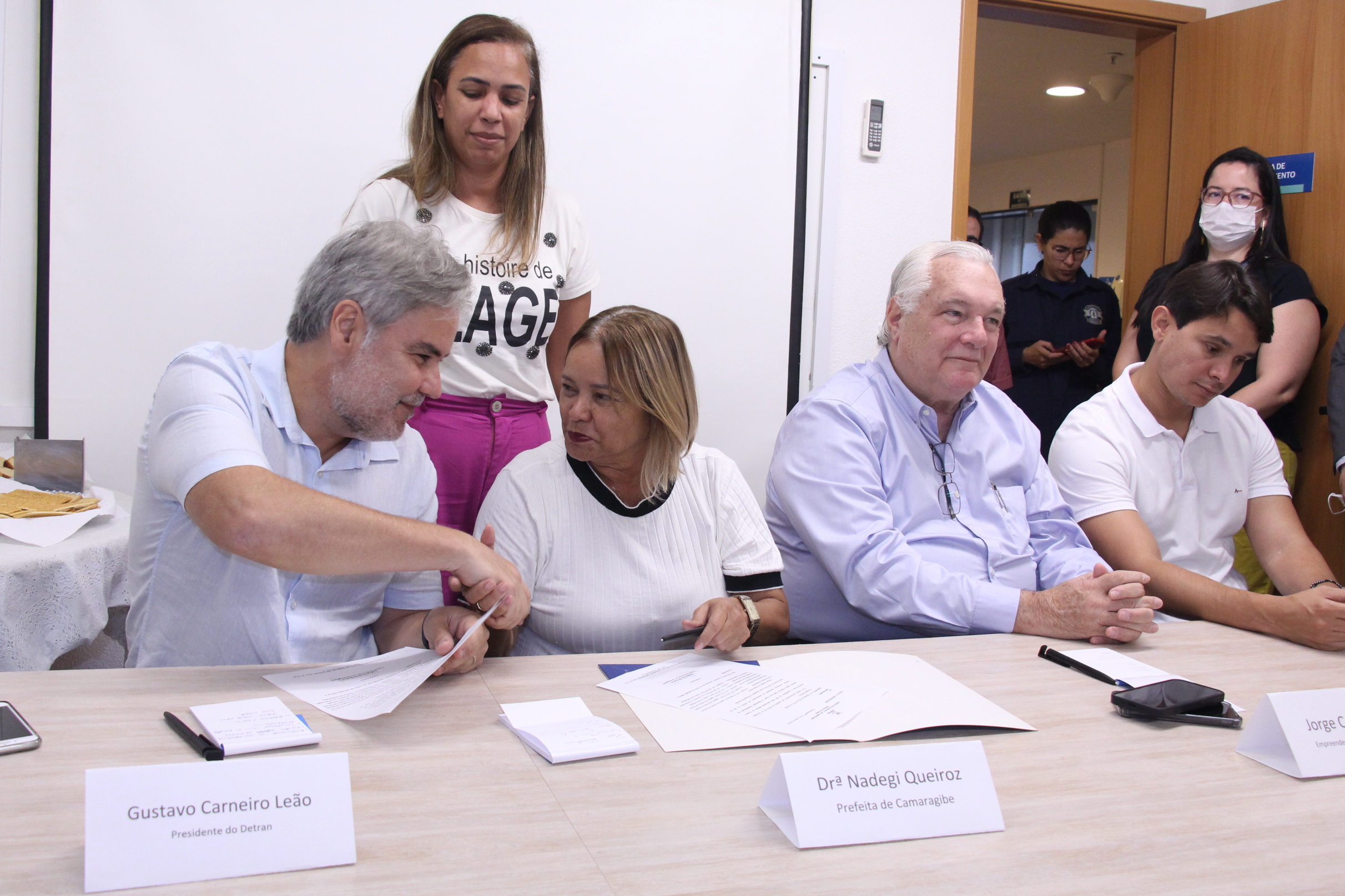 Na foto, o Diretor Presidente do DETRAN-PE, Gustavo Carneiro Leão, está apertando a mão da  Prefeita de Camaragibe, Nadegi Queiroz. Na ocasião, ele recebeu a lista de funcionários cedidos da prefeitura para realizar treinamento e posterior trabalho na da Autarquia no Camará Shopping. Fazendo parte da mesa, estão o Empreendedor do Camará Shopping, Jorge Corte Real, e o Deputado Estadual eleito, João Victor. 