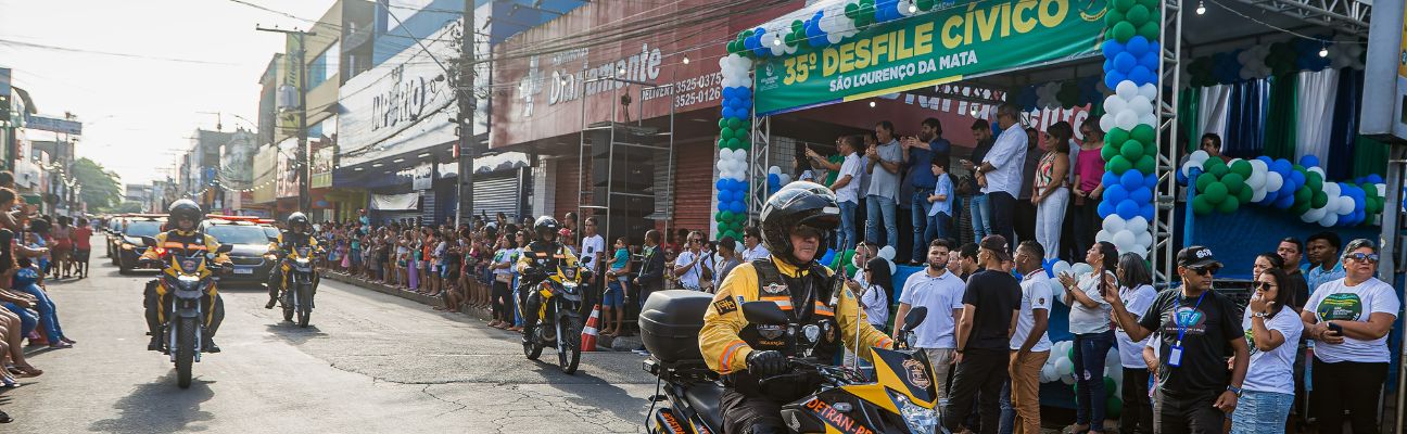 Na foto, motocicletas viaturas e carros viaturas da fiscalização do DETRAN-PE desfilando no 35º Desfile Cívico em  São Lourenço da Mata, passando em frente ao palanque. 