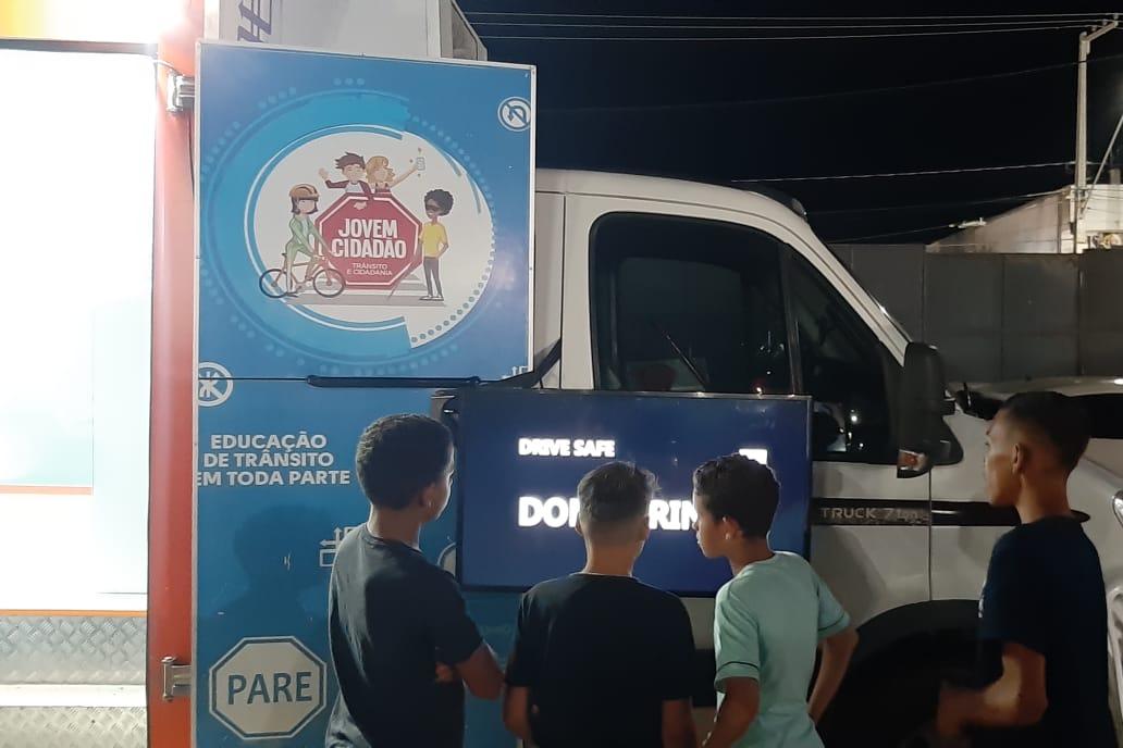 Crianças lendo placa na unidade do Detran Itinerante