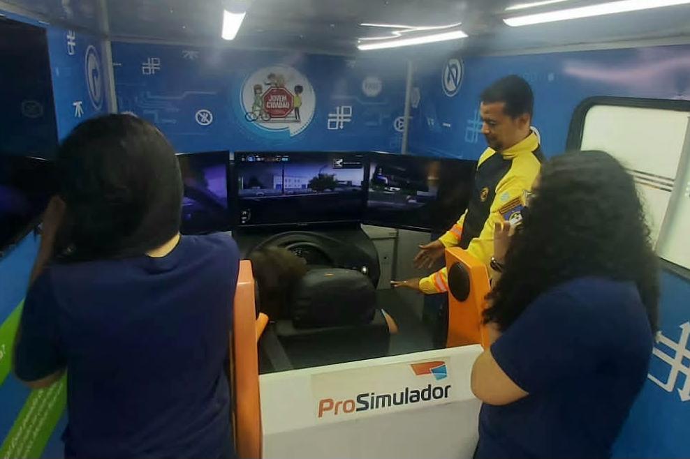 Estudantes utilizando simulador com instrução de agente de trânsito