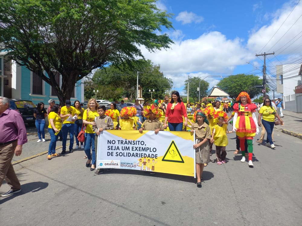 Alunos segurando placa com os dizeres: No trânsito seja um exemplo de solidariedade
