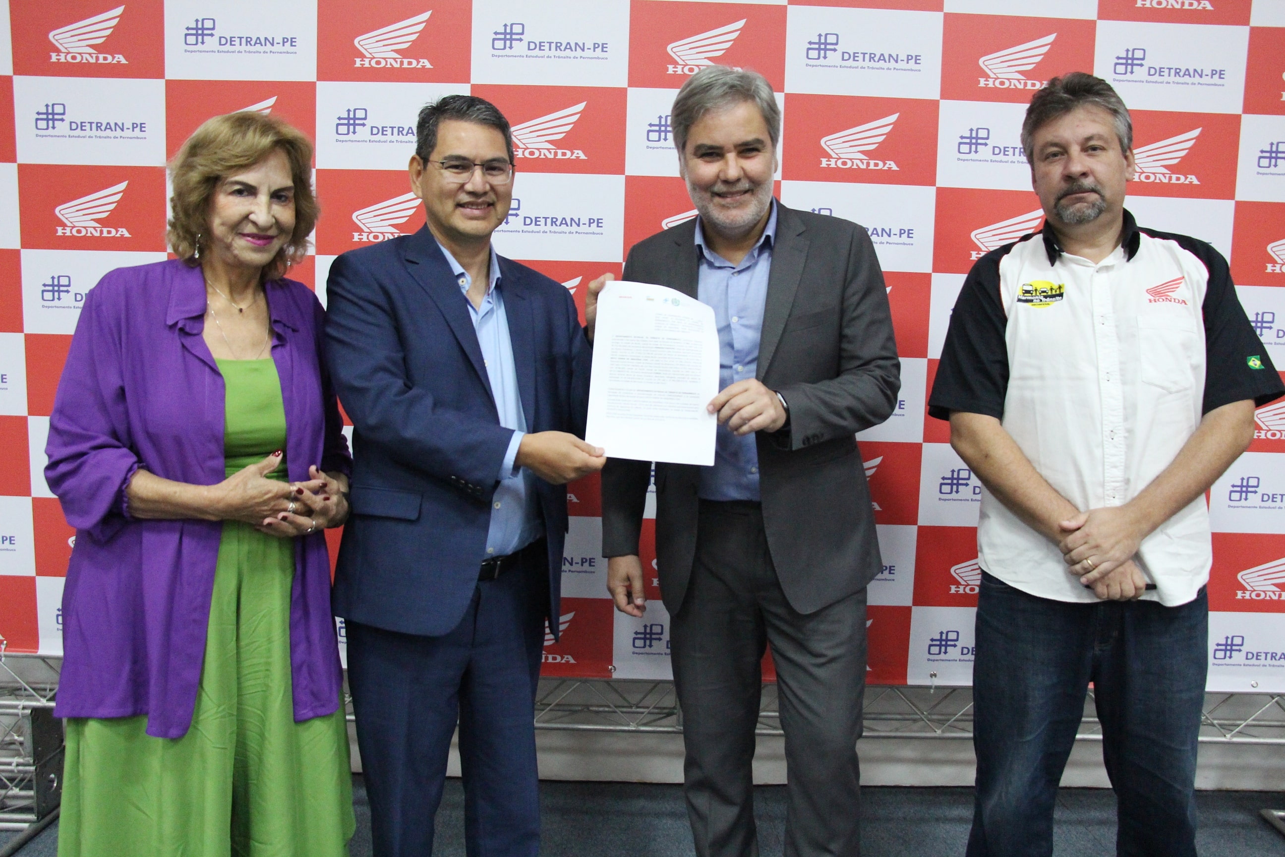 Diretor Presidente do Departamento Estadual de Trânsito - DETRAN-PE, Gustavo Carneiro Leão, e o Diretor de Relações Institucionais da Moto Honda da Amazônia, Marcos Bento, segurando Termo de Cooperação Técnica do DETRAN-PE com a Honda. Na foto, também estão a Coordenadora de Educação de Trânsito, Imprensa e Publicidade Institucional do DETRAN-PE, Jô Lima, e o Gerente das Unidades dos Centros Educacionais de Trânsito da Honda Brasil, Leonardo Donato.