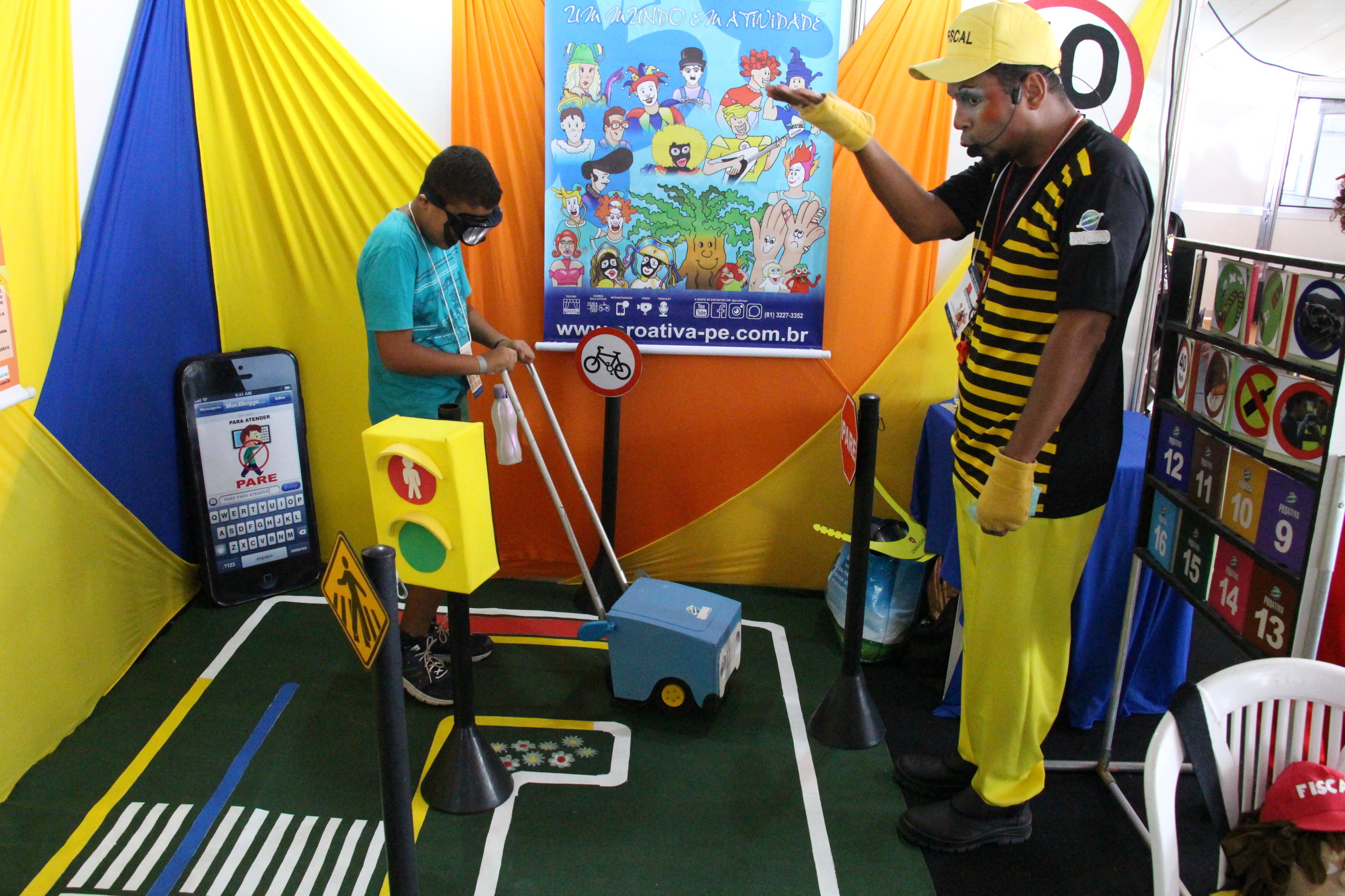 Na foto, arte educador da Prefeitura de Camaragibe realizando ação educativa com criança, na 20º Feira de Educação para o Trânsito de Pernambuco, que acontece na Praça de Eventos de Camaragibe.
