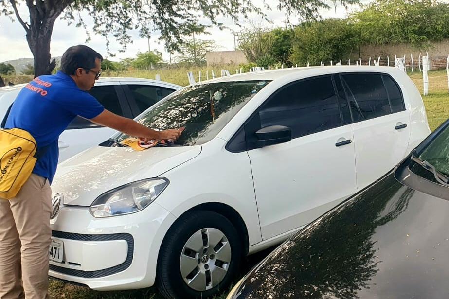 Na foto, educador de trânsito do DETRAN-PE realizando ação em carro, em Fazenda Nova, no espetáculo da Paixão de Cristo, quando foram colocados folders educativos nos veículos. 
