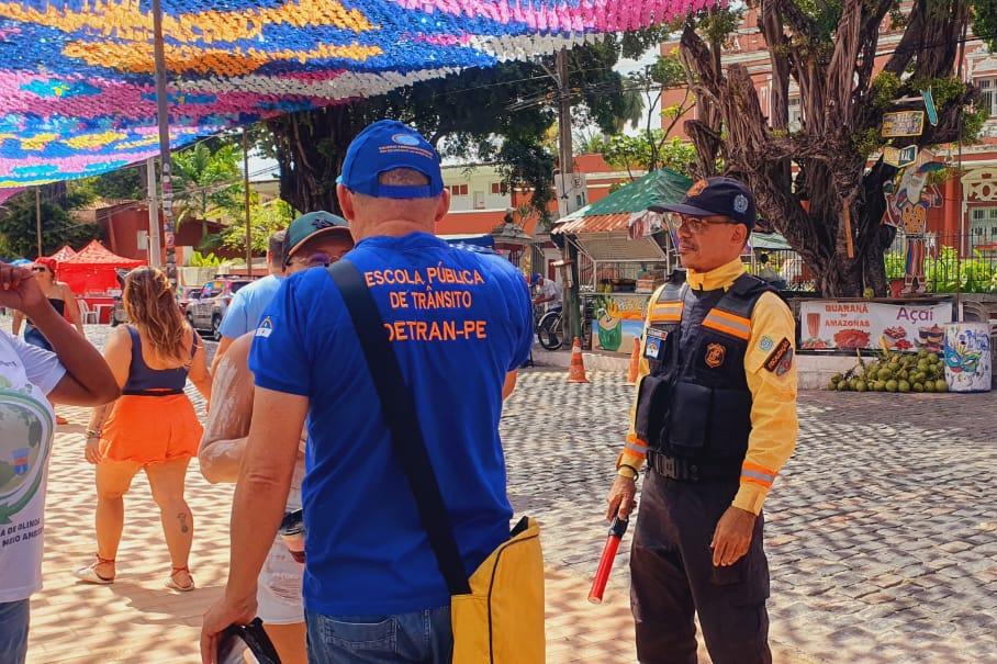 Na foto, educador de trânsito e agente de trânsito do DETRAN-PE realizando ação educativa nas prévias de carnaval em Olinda.