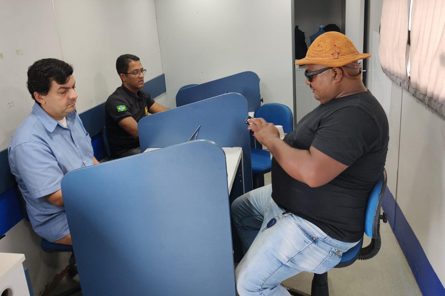 Na foto, dois servidores do DETRAN-PE e um usuário, no caminhão do Detran Itinerante. 
