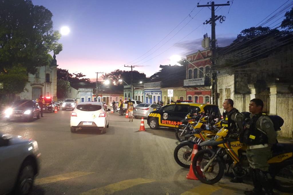 Na imagem, blitz coercitiva do DETRAN-PE com vários veículos passando, ao fundo, agentes de trânsito do DETRAN-PE e policiais militares estão fazendo a fiscalização.