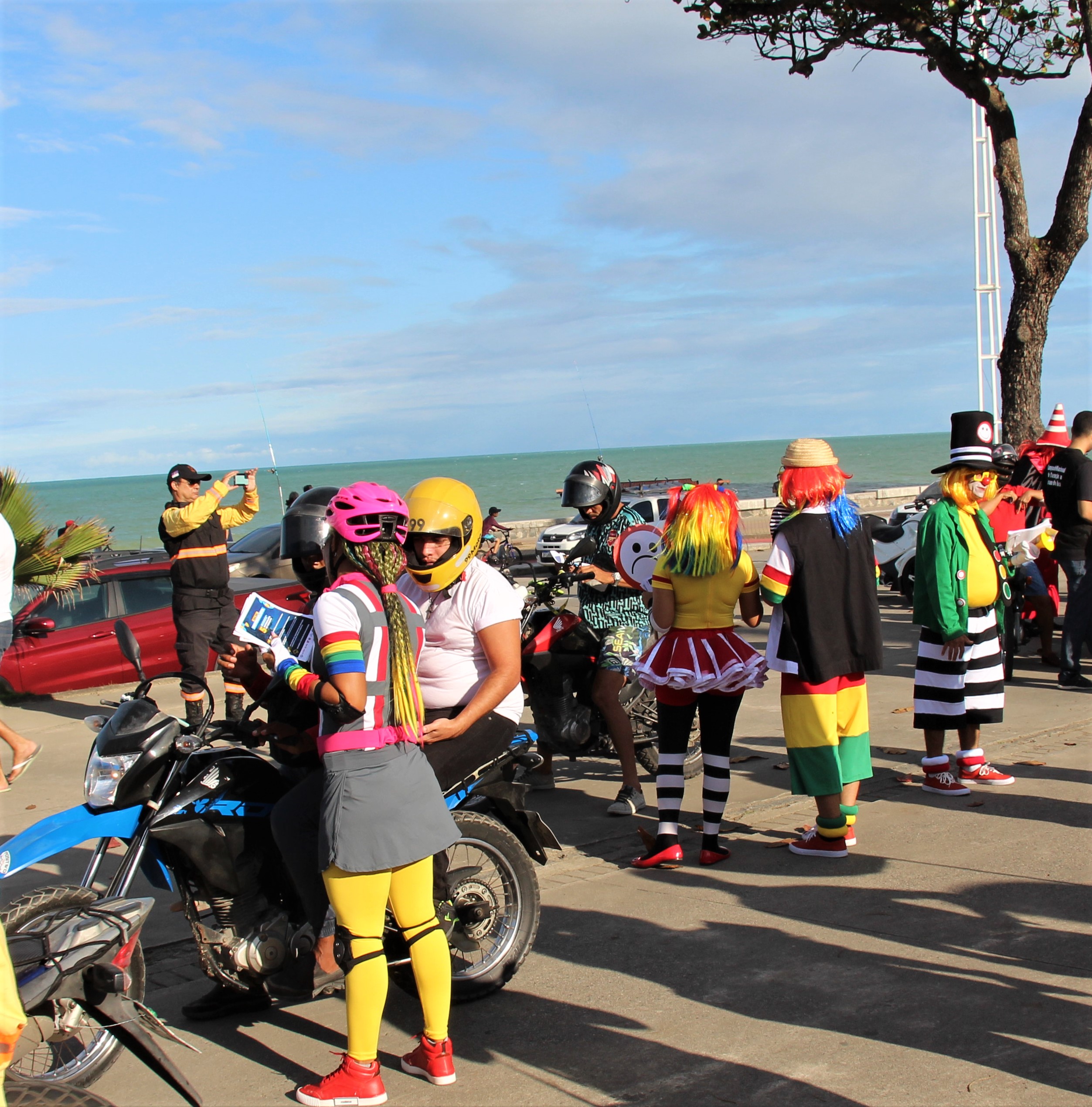 Fotografia colorida mostra os palhaços da turma do Fom Fom em ação com motociclistas no Parque Dona Lindu