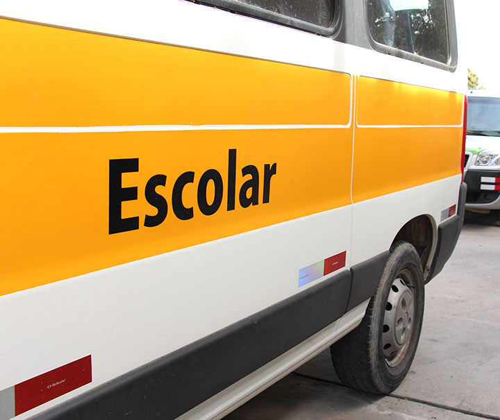 Imagem com veículo com faixa amarela pintada e a palavra Escolar ao centro
