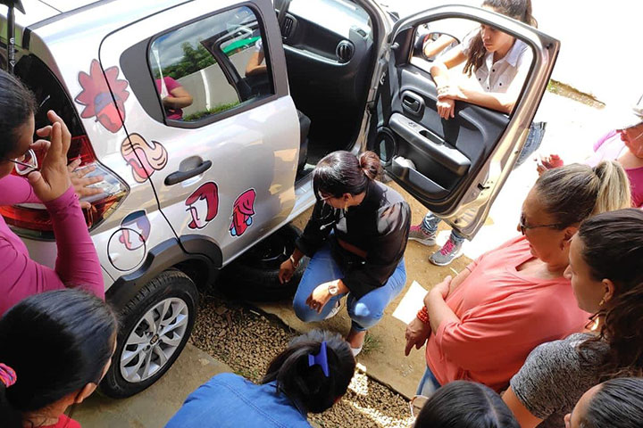 foto de mulheres ao redor de um carro recendo instruções do curso prático de mecânica de automóveis para mulheres